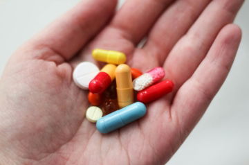 orange and white medication pill on persons hand